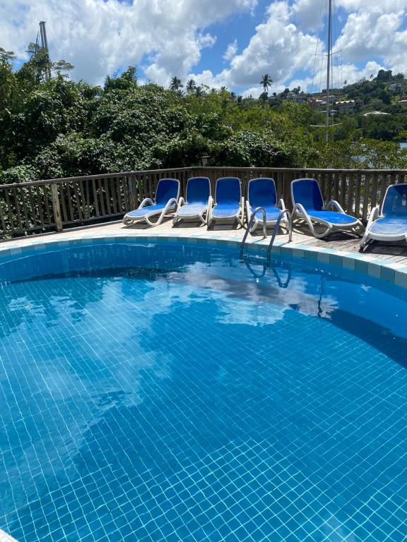 una piscina con sillas azules y un montón de agua en Blue Bamboo cottage Marigot Bay. en Marigot Bay