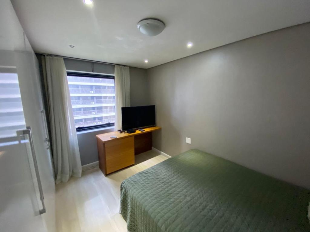 a bedroom with a bed and a flat screen tv at Flat Moema Jamaris in São Paulo