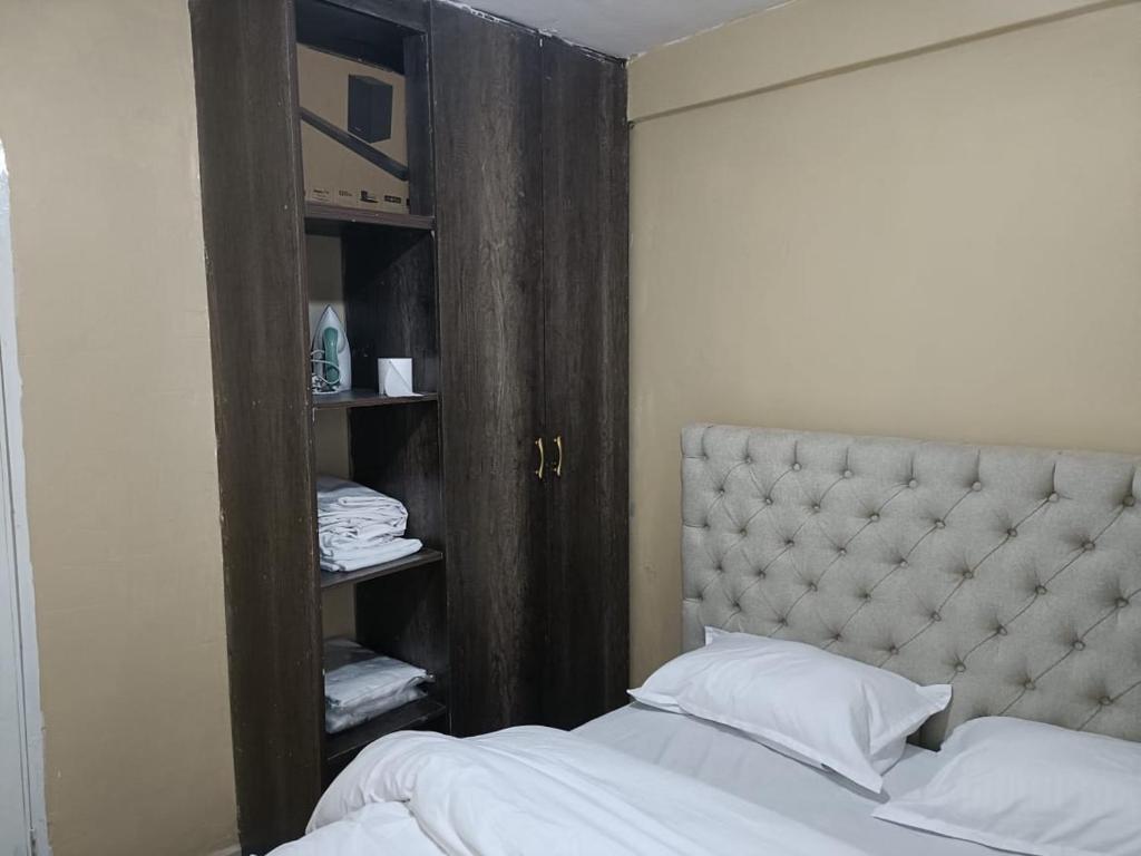 Schlafzimmer mit einem Bett und einem Holzschrank in der Unterkunft D.S Apartment in Kakamega