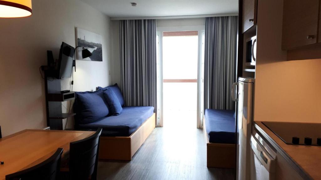 un salon avec un canapé bleu et une table dans l'établissement Résidence Port du Crouesty - maeva Home - 2 Pièces 7 Personnes - Confort MAE-2873, à Arzon