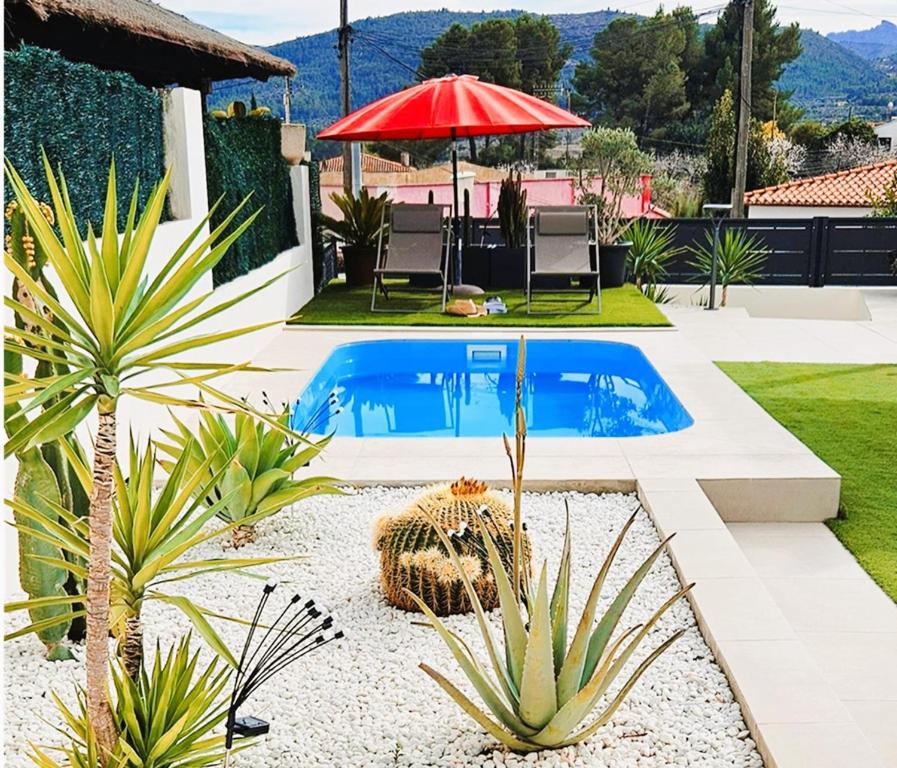 una piscina en un patio trasero con plantas y sombrilla en Casa Galia en Alcalalí