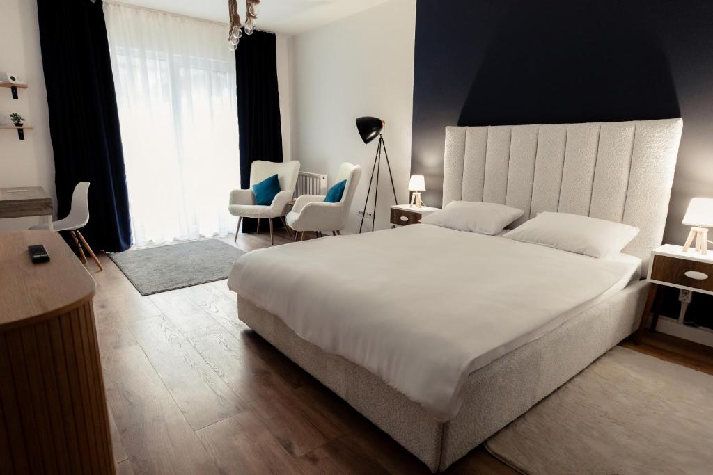 een slaapkamer met een groot wit bed en stoelen bij Blue Harmony Apartment in Floreşti