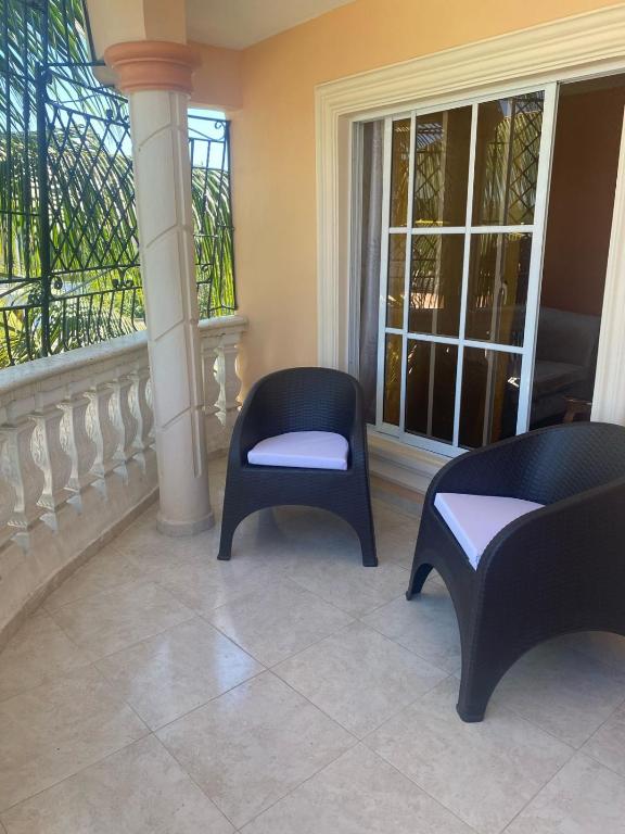 Habitación con 2 sillas y balcón con ventanas. en Quiet space II, en San Cristóbal