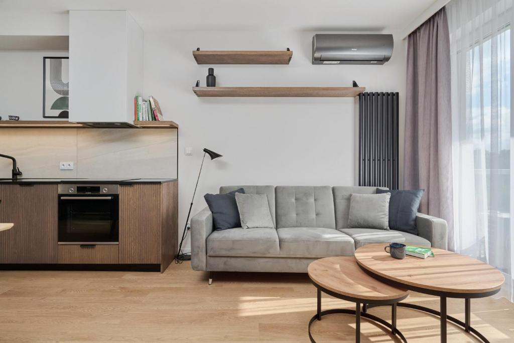 uma sala de estar com um sofá e uma mesa em Białowieska 69 - Ekskluzywny apartament w Porcie Popowice z parkingiem i balkonem - Fair Rentals em Breslávia