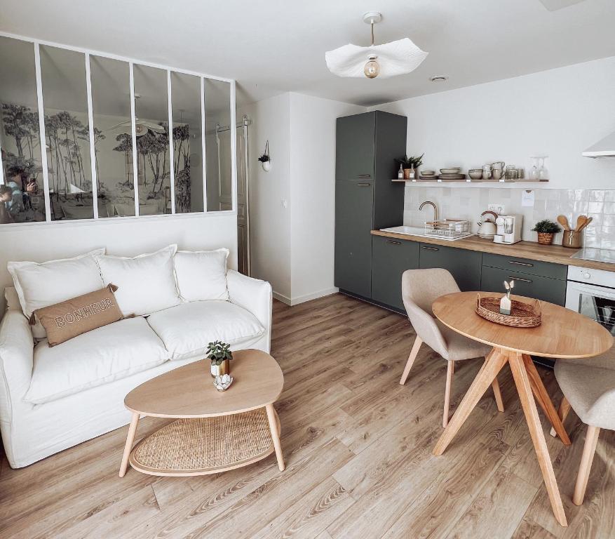 Il comprend un salon avec un canapé et des tables ainsi qu'une cuisine. dans l'établissement Studio cosy, proche Poitiers, à Nieuil-lʼEspoir