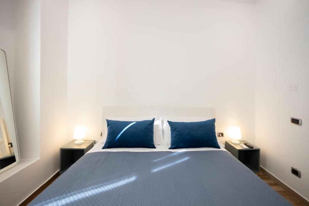 Un dormitorio con una cama con almohadas azules y dos lámparas. en Tredidenari B&B, en Salerno