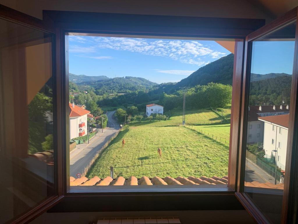 ein Fenster mit Blick auf ein Grasfeld in der Unterkunft Apto Valle Encantado, vistas preciosas en urbanización con piscina in Gibaja