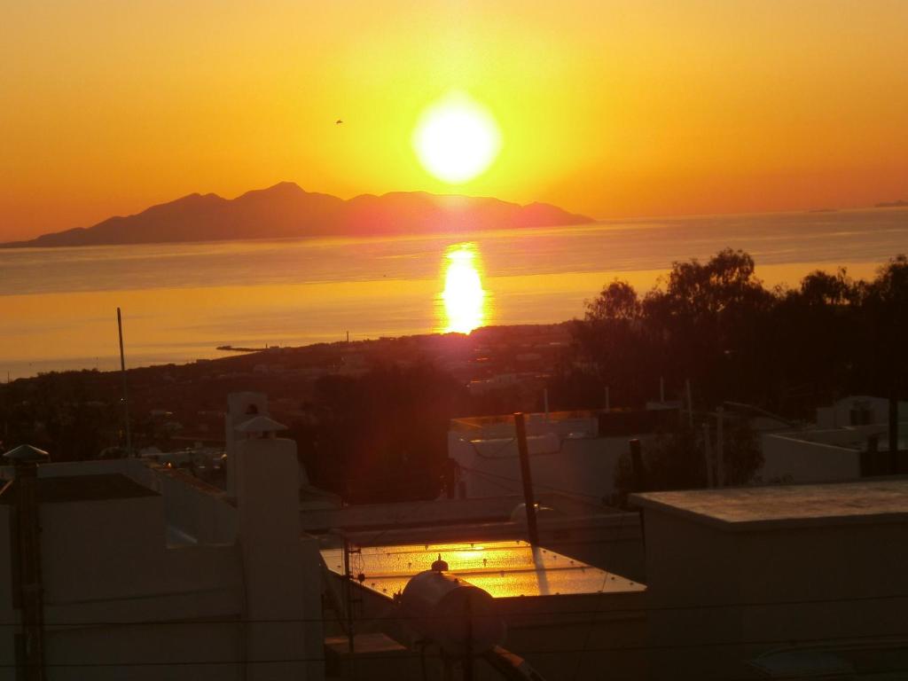 フィラにあるAratos Apartments - Kallisto 2bedroom Apartmentの屋根に立って夕日を眺める男