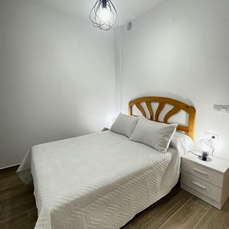 a bedroom with a white bed and a night stand at Bajo Derecha el Wiro in Puerto