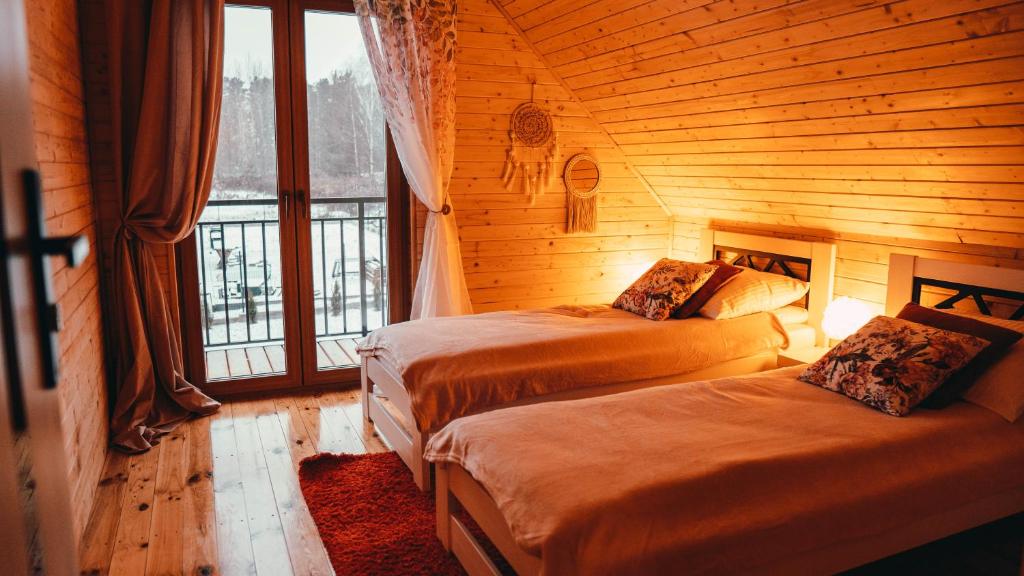 a bedroom with two beds in a log cabin at Gwiazda Północy Gołdap Dom VIP na Wynajem in Gołdap