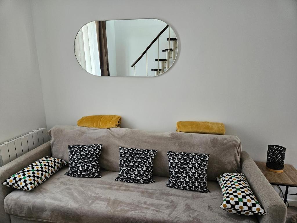 - un salon avec un canapé, des oreillers et un miroir dans l'établissement Duplex Stade de France 23 pour 4 personnes, à Saint-Denis