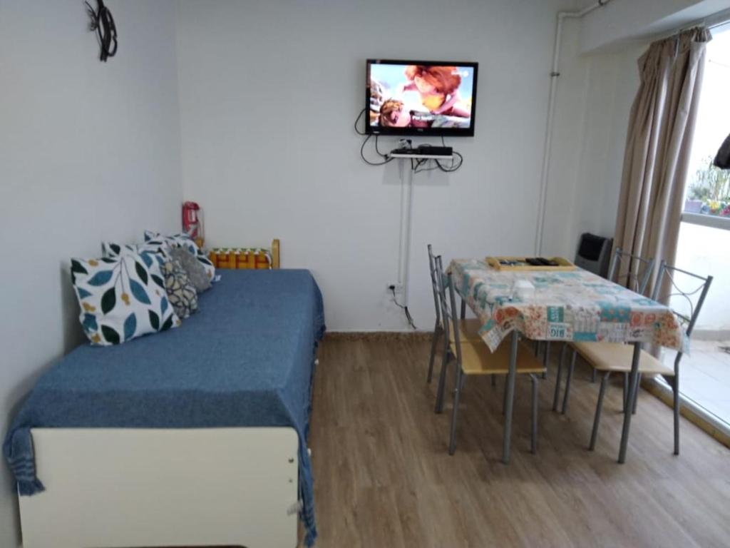 a room with a bed and a table and a television at Inmejorable ubicación frente al mar in Puerto Madryn