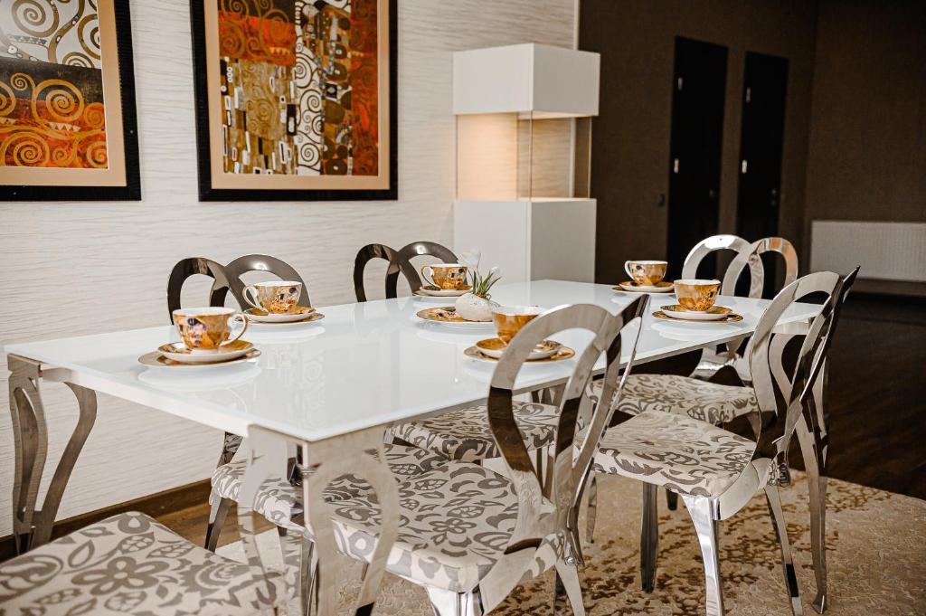 a white table with chairs and cups and plates on it at Spacious apartment close to Valea Trandafirelor park in Chişinău