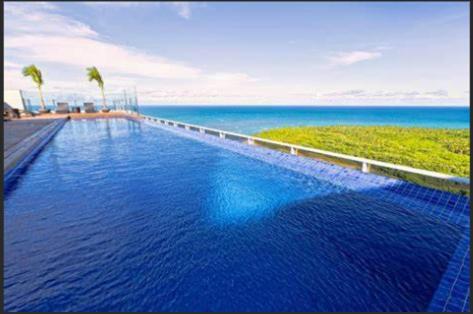 勒西菲的住宿－BUGAN PAIVA RECIFE，一个大型的游泳池,背景是大海