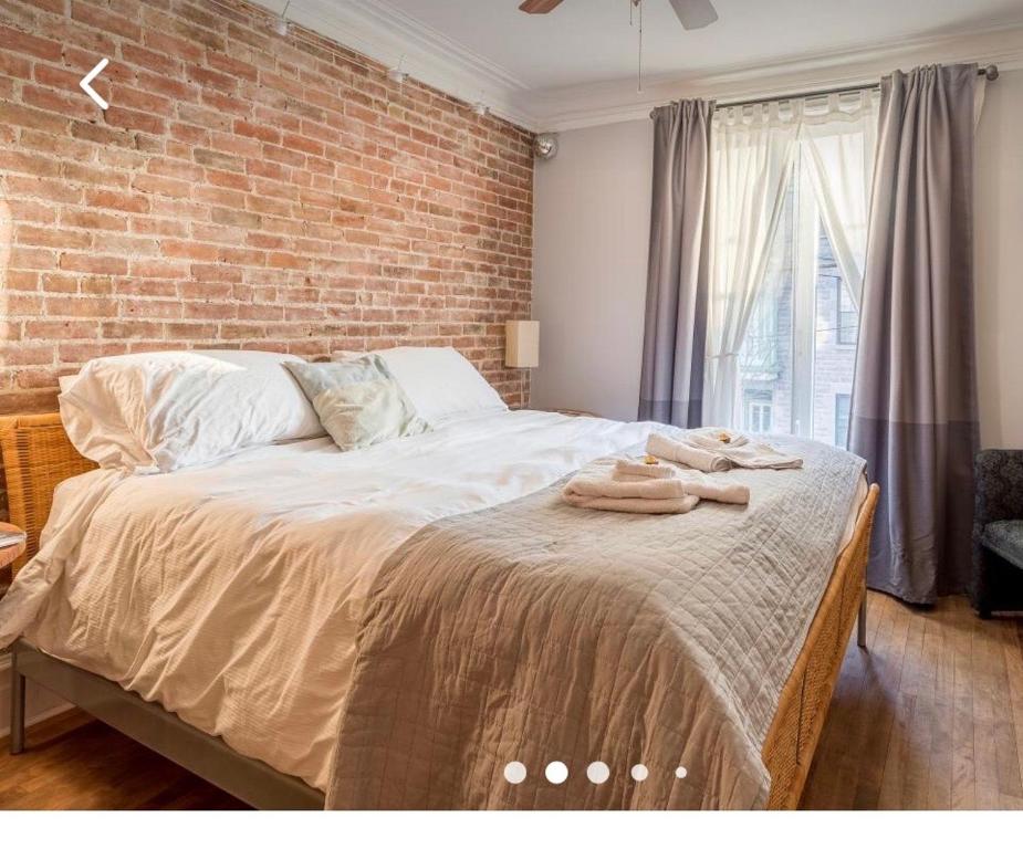 1 dormitorio con 1 cama grande y pared de ladrillo en Cozy Montreal Suites in Prime Location en Montreal