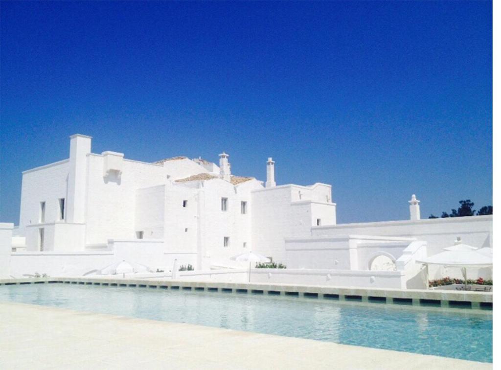 a white building with white walls and a blue sky at Masseria Le Carrube in Ostuni