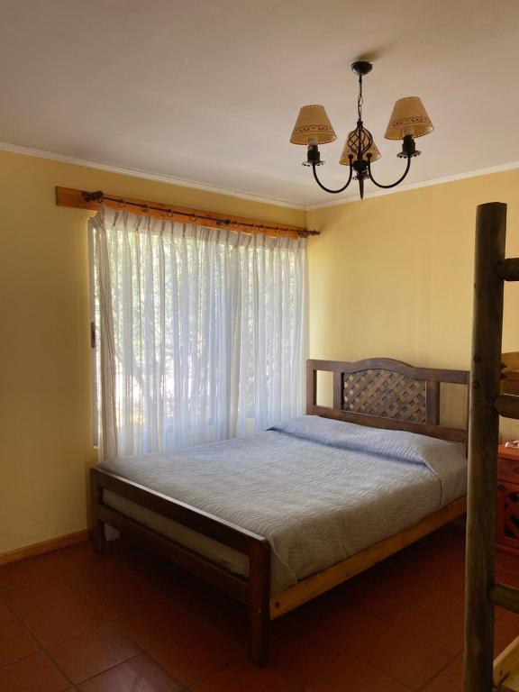 a bedroom with a bed with a window and a chandelier at Casaelqui in Vicuña