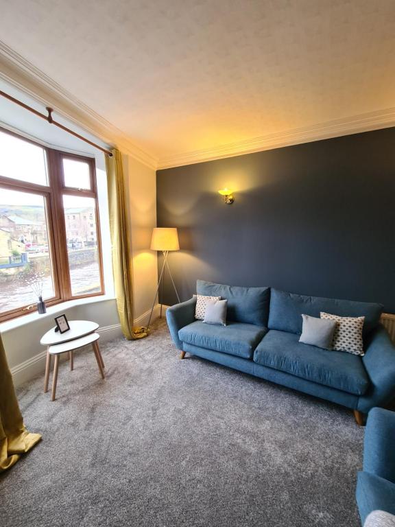 een woonkamer met een blauwe bank en een raam bij Stunning River View in Mytholmroyd