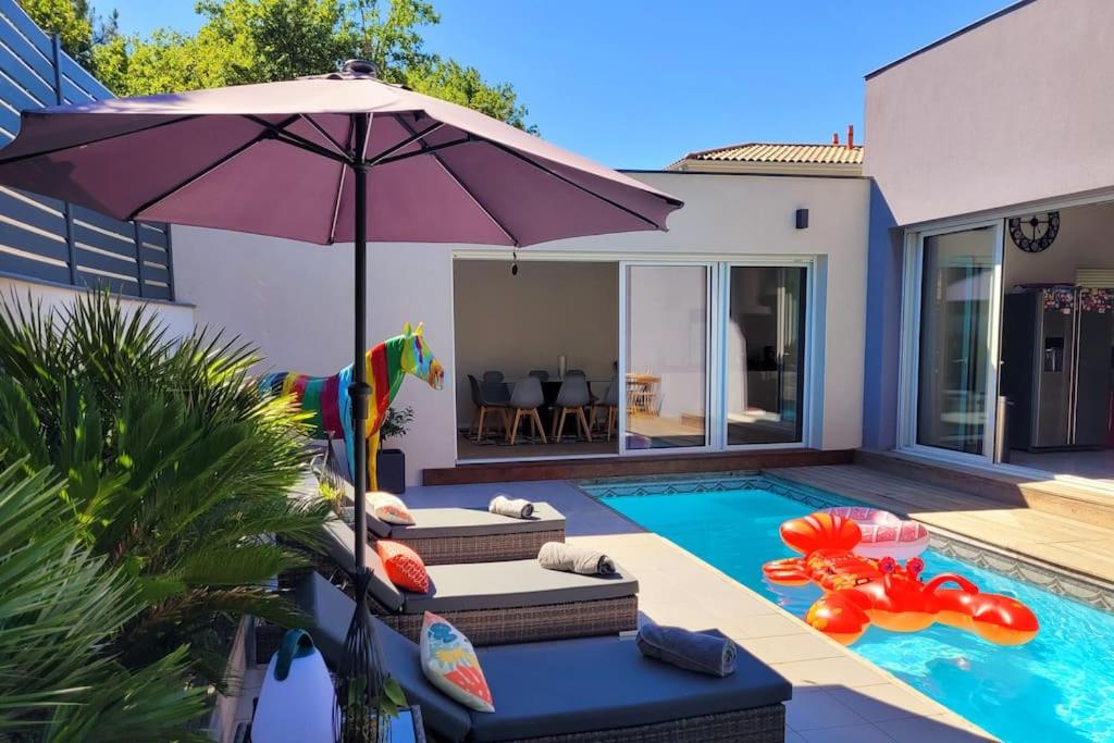 a house with a swimming pool with an umbrella at Magnifique maison d'architecte Bordeaux Mérignac in Mérignac