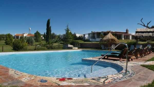 una gran piscina con sombrilla y sillas en Complejo Turístico Casaflor en Villa Cura Brochero