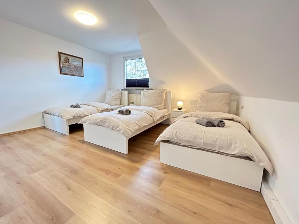 two beds in a room with white walls and wooden floors at Zentrale Wohnung I 5G Internet I Netflix I in Iserlohn