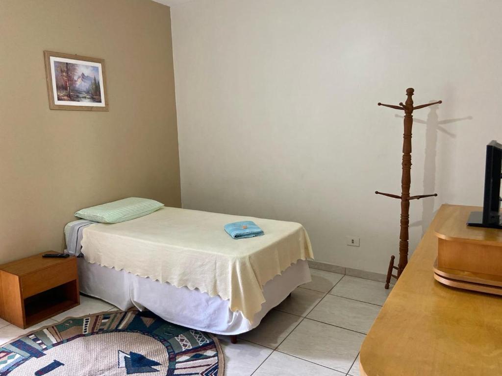 um pequeno quarto com uma cama e uma cruz na parede em Quarto com banheiro e sem café e sem TV no Edifício Verona em Fazenda Rio Grande
