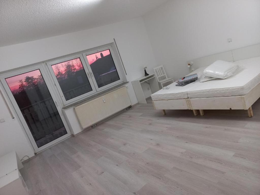 an empty room with a bed and three windows at hoteliving am Bahnhof in Pohlheim