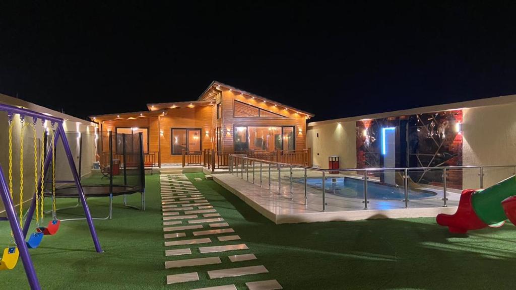 un edificio con parco giochi di notte di أكواخ وشاليهات ذا فيلج - The village a Khalij Salman