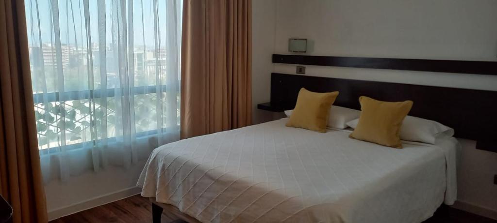 a bedroom with a bed with yellow pillows and a window at Apart Hotel Inga Providencia in Santiago