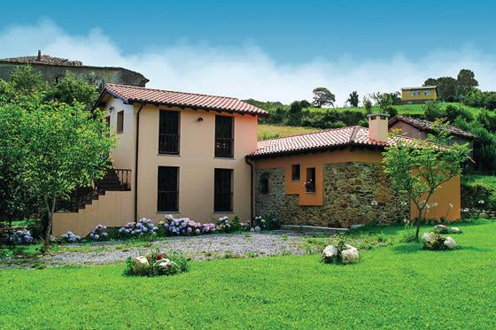 a house in a yard with a green lawn at Apartamentos Rurales El Molín de Panizal in San Cosme