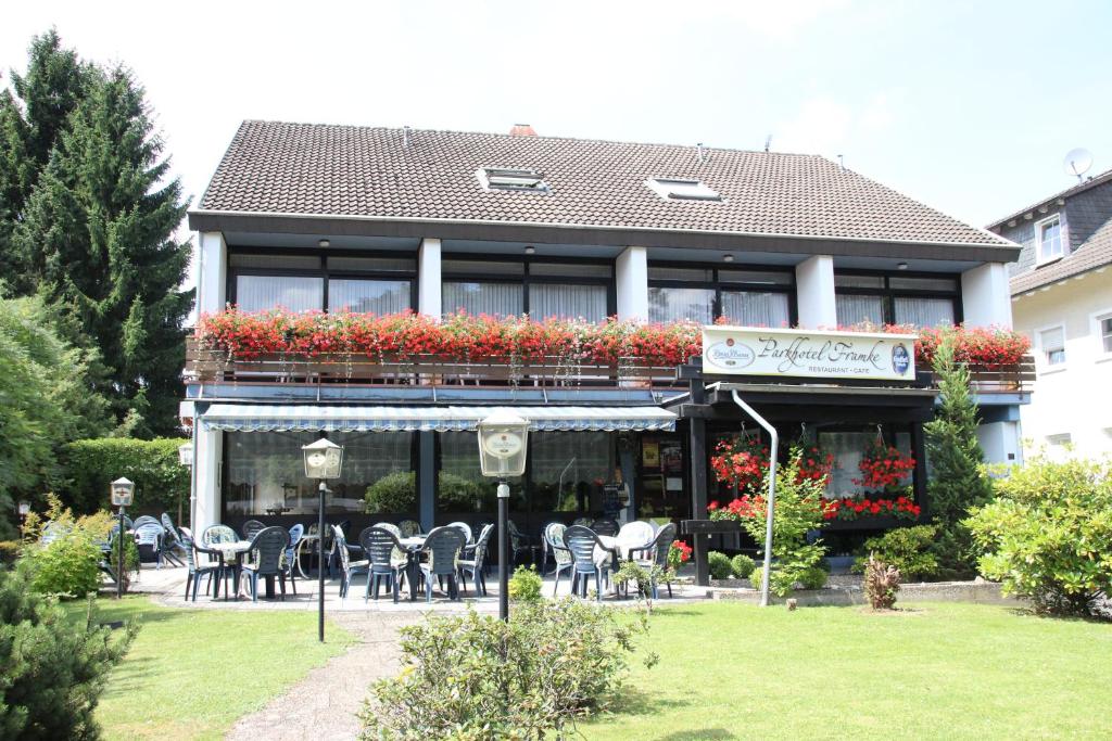 a building with tables and chairs in a garden at Parkhotel Framke in Ehlscheid