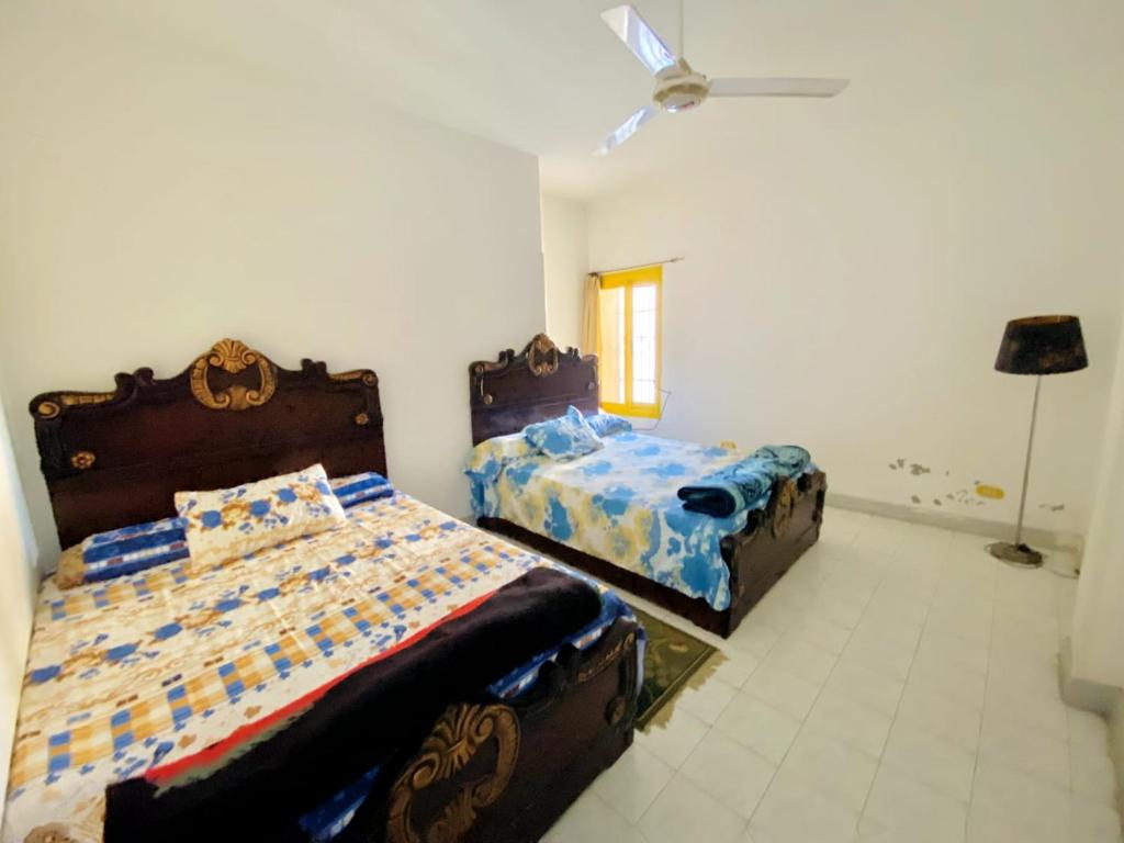 1 dormitorio con 2 camas y ventilador de techo en فيلا in fayed en ‘Ezbet el-Ibrâshi