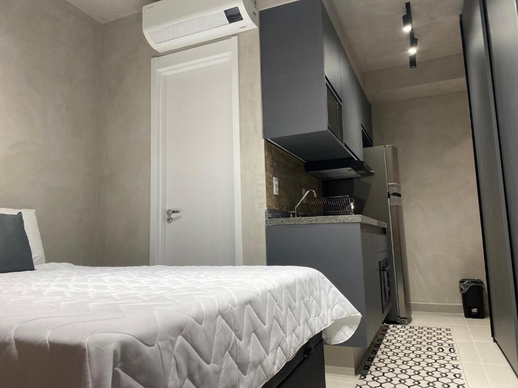 Hotel Apartamento novo no Brooklin, a small room with a bed and a kitchen at Apartamento novo no Brooklin in São Paulo
