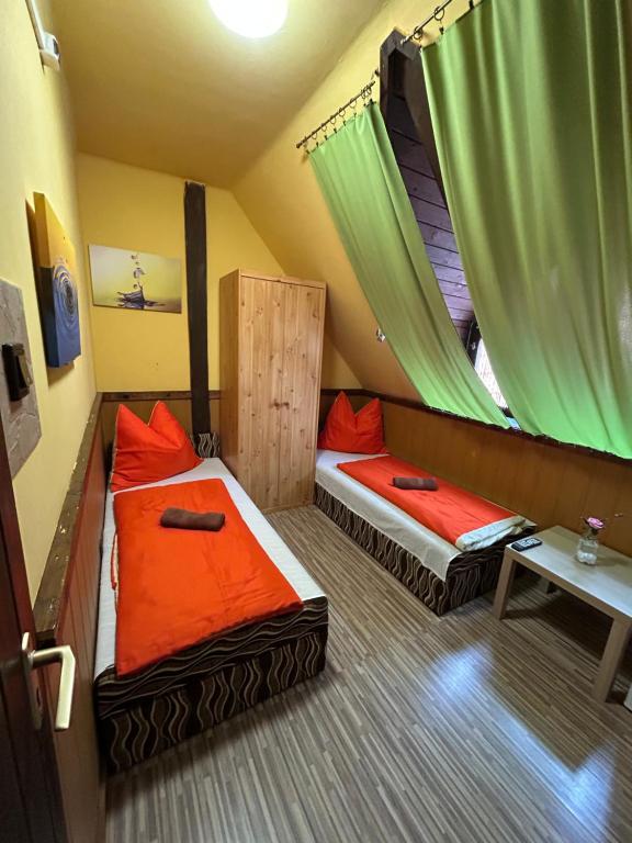 two beds in a small room with green curtains at Vakáció Üdülő in Révfülöp