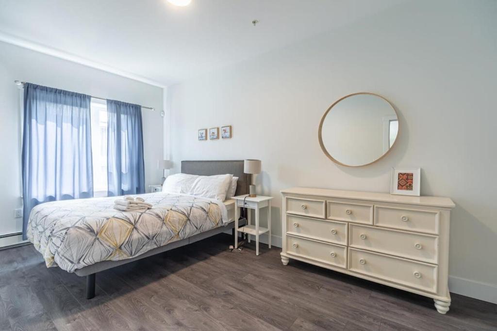 Schlafzimmer mit einem Bett, einer Kommode und einem Spiegel in der Unterkunft Spacious & Stylish Apt #1 with AC in Halifax