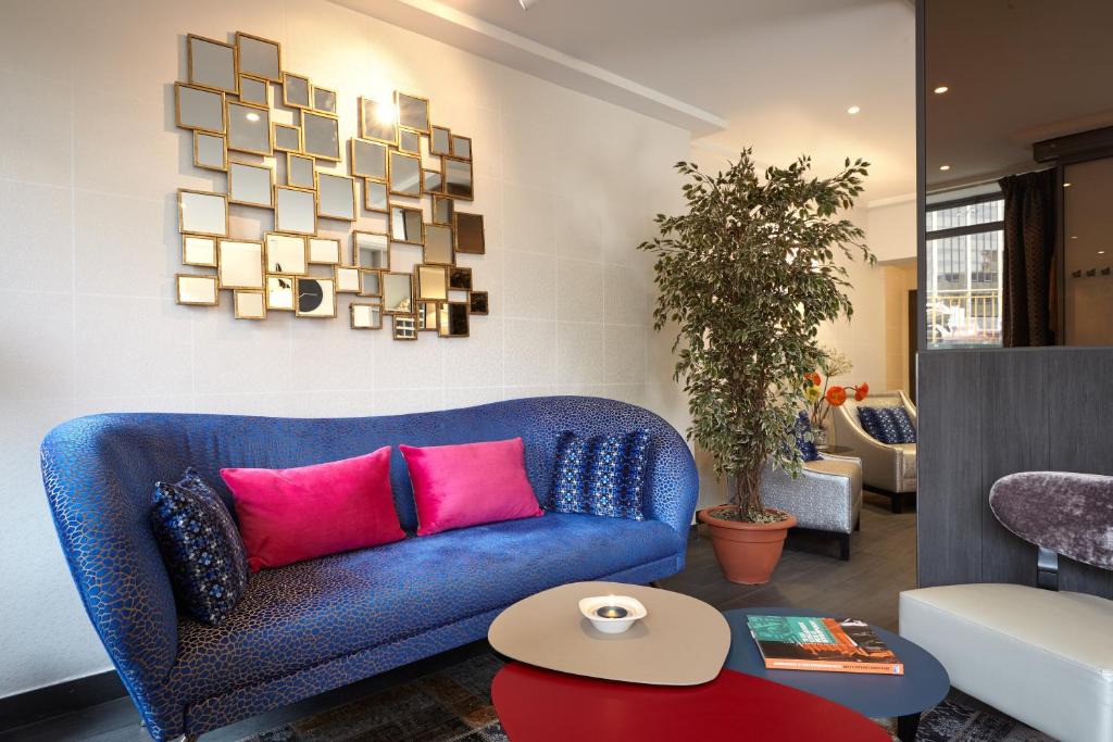a living room with a blue couch and pink pillows at Hotel Miramar in Paris