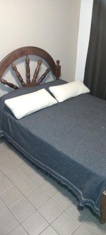 1 cama con cabecero de madera y 2 almohadas en QUIRUS DORMIS en Villa Carlos Paz