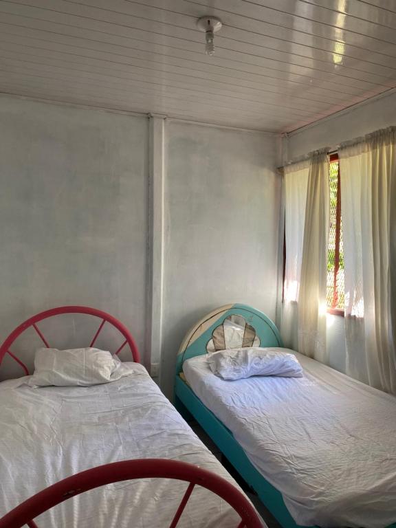 2 camas en una habitación pequeña con ventana en Casa Irene, en Orotina