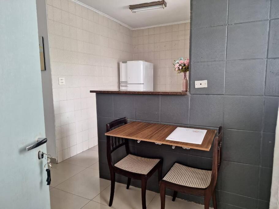 eine Küche mit einem Tisch, 2 Stühlen und einem Kühlschrank in der Unterkunft Apto a dois quarteirões da praia da Enseada in Guarujá