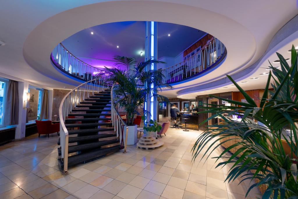 un hall avec des escaliers et des plantes dans un bâtiment dans l'établissement Hessenland Hotel Kassel Innenstadt by Stay Awesome, à Cassel