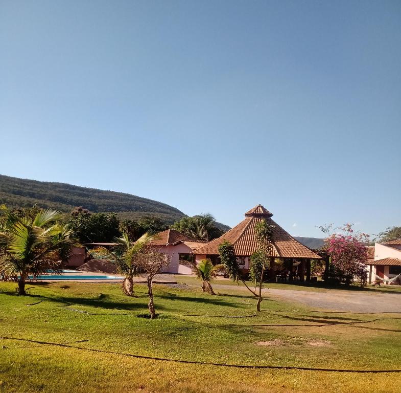 a group of houses with palm trees in a field at Pousada e restaurante Jardim do Cerrado in Nobres