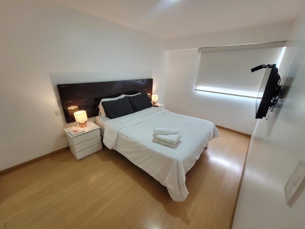 Dormitorio pequeño con cama blanca y espejo en Espacio Luxury Apartments- Bolivar 02, en Lima