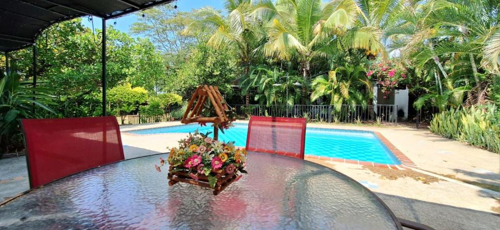 - une table en verre avec des fleurs à côté de la piscine dans l'établissement RV Finca a 20 min de Neiva, à Neiva