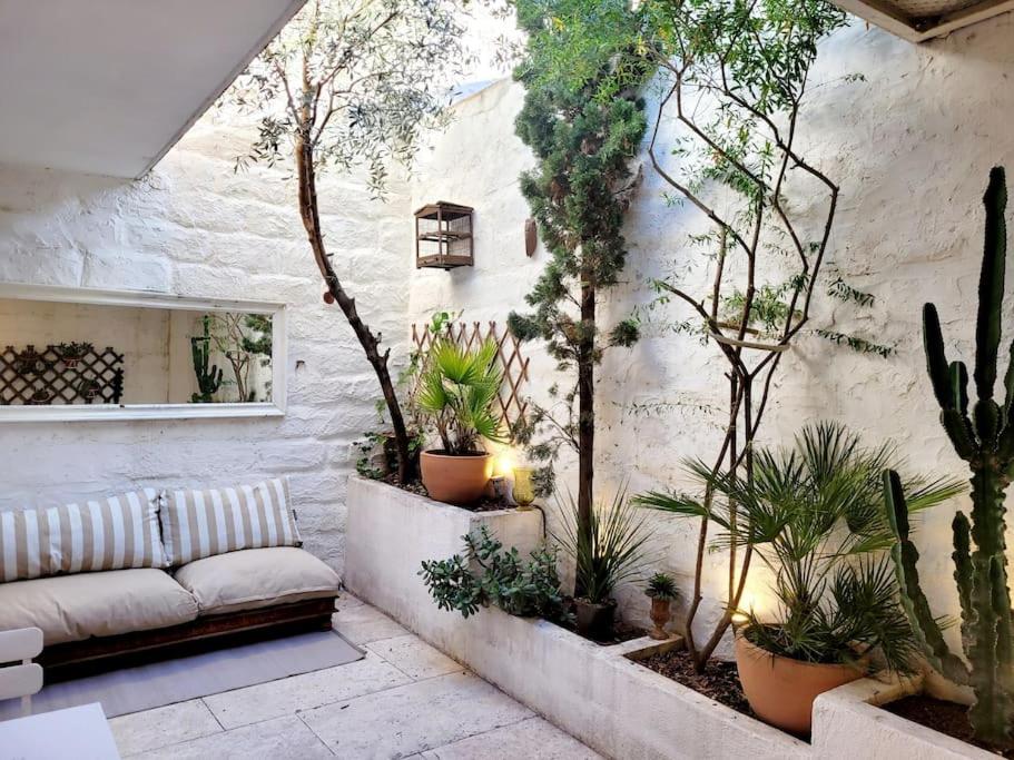 a patio with a couch and a bunch of plants at La maison blanche Intra-Muros Free parking in Aigues-Mortes
