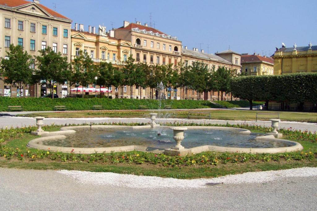a fountain in a park in front of a building at Apartments with a parking space Zagreb - 22231 in Zagreb