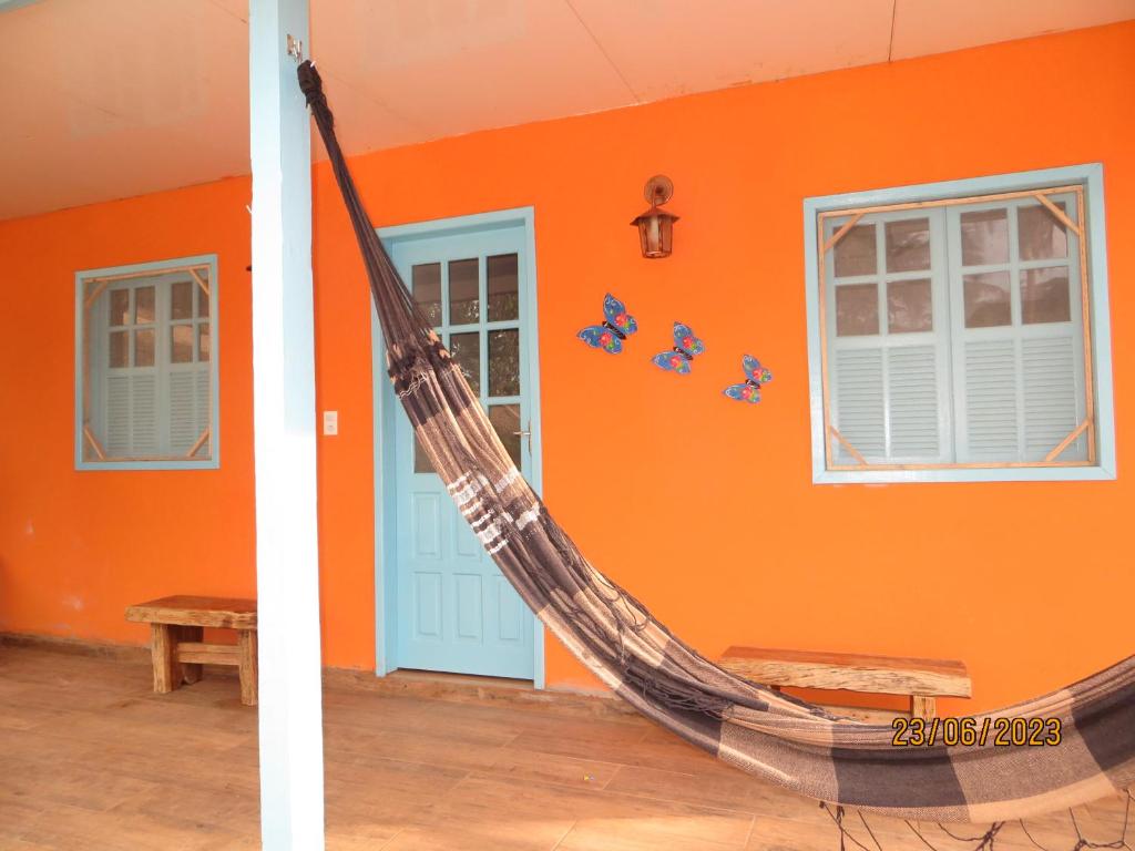 a hammock in a room with an orange wall at Pousada Usina Paraíso in Astolfo Dutra