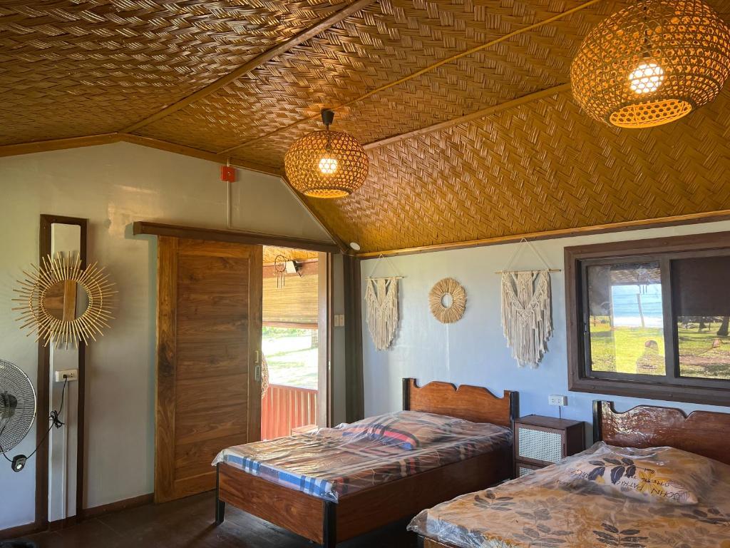 New Agutaya的住宿－The Beach House Long Beach，一间卧室设有两张床、两扇窗户和两盏灯。
