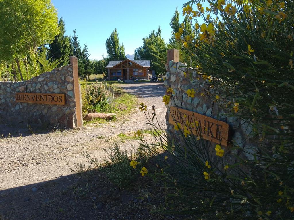 a sign on a stone wall with a building in the background at Ushua Aike (Nuestro Lugar) in Los Antiguos