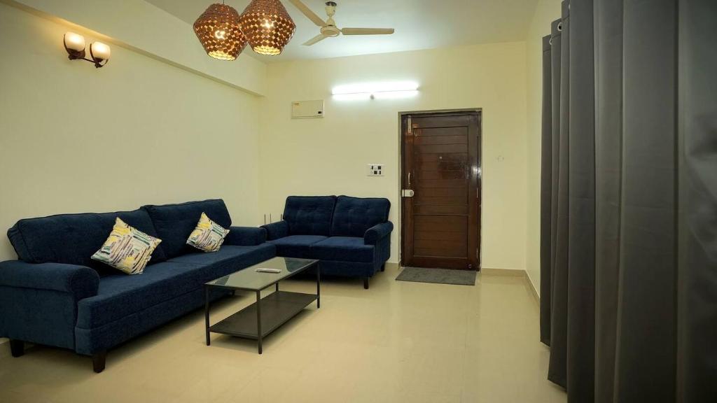 sala de estar con sofá azul y mesa en Deltin Royal Stays 3 Bedroom Apartment, en Hyderabad