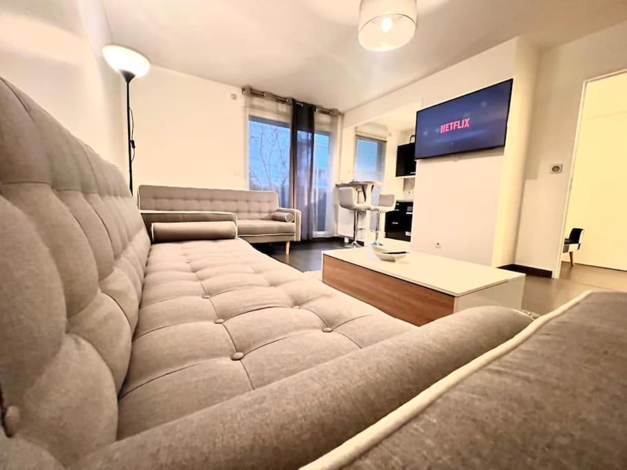 a living room with a couch and a flat screen tv at Créteil - Pointe du Lac - Le So’ in Créteil